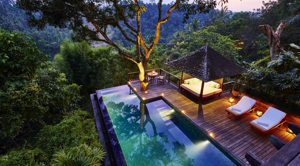 The pool, wooden deck and deck chairs at the Como Shambala Estate in Ubud