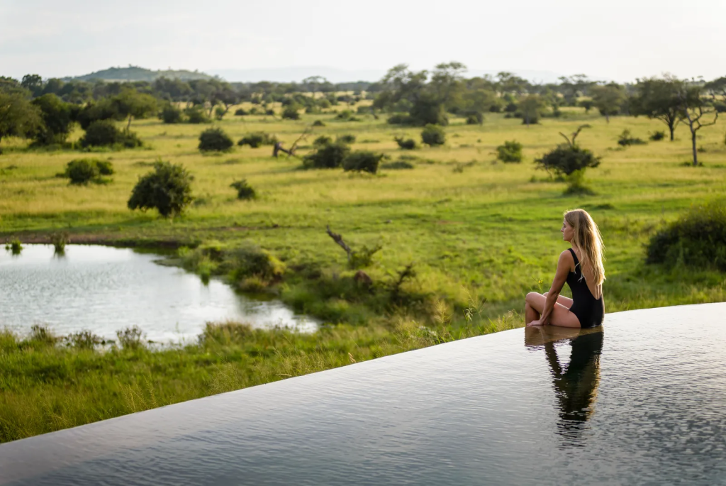 A women sitting on the edge of the infinity pool of Singita Faru Faru Lodge in Tanzania