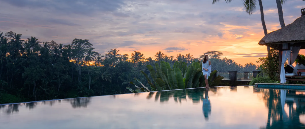 A woman posing by the pool at sunset