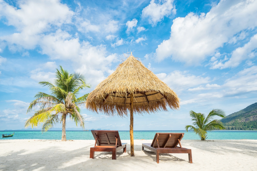 Two sun loungers and a straw umbrella on a white sand beach in Zanzibar