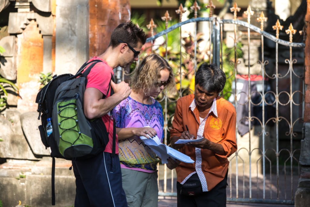 A local Balinese man assisting tourists with a tourist attraction