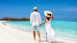 A couple on their honeymoon holding hands on a pristine white beach