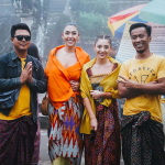 Tourists standing with local Balinese in front of a traditional temple